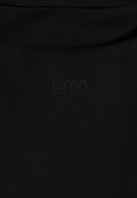 Črn material z gladko teksturo ima majhen, vtisnjen logotip "amn". Oblika je preprosta in brez okrasja.