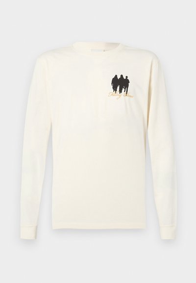 Langermet kremfarget bomull t-skjorte med sort silhuettdesign av tre figurer og gulltekst "Filling Spaces" på fronten.