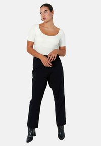 White short-sleeve scoop-neck bodysuit paired with high-waisted black trousers, featuring a straight leg and shiny black ankle boots.