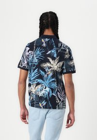Chemise noire à manches courtes avec un motif tropical coloré featuring des feuilles de palmier et des oiseaux, fabriquée en tissu léger.