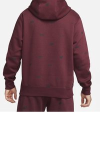 Maroon hoodie featuring a textured fabric, large hood, and repeated dark logo patterns. Designed with ribbed cuffs and hem.