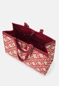 Sac fourre-tout rouge et beige avec un motif tissé. Comprend des poignées en cuir, un intérieur ouvert et une poche intérieure zippée. Confection en tissu durable.