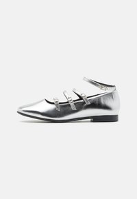 Ballerines métalliques argentées avec un bout pointu, trois brides réglables et un petit talon noir. Texture lisse avec un design minimaliste.