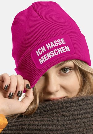Fuchsia knit beanie with a white patch displaying "ICH HASSE MENSCHEN." Features ribbed texture and a fold-over cuff.