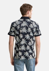 Camisa de manga corta en azul marino oscuro con un patrón de palmeras claras. Cuenta con un cuello de punto y una tela suave para mayor comodidad. Diseño de corte clásico.