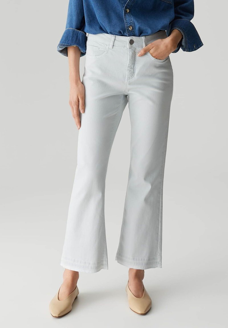 Lichtgrijze flared jeans van denim, met een klassiek vijf-pocket ontwerp en een knoopsluiting. In combinatie met beige instap schoenen.