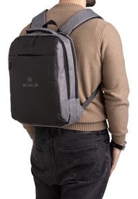 Zaino nero e grigio, design rettangolare, realizzato in tessuto resistente, dotato di tasca frontale con zip, spallacci regolabili e dettaglio del logo.