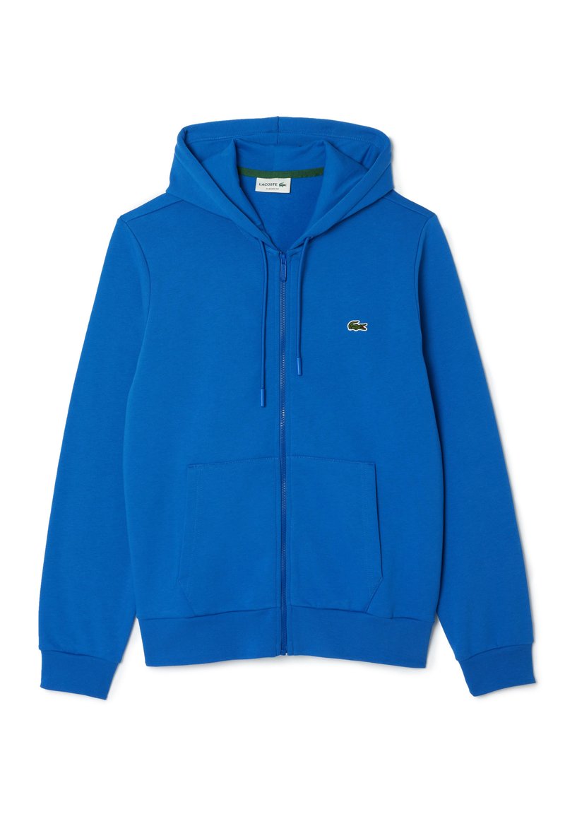 Felpa blu con zip realizzata in tessuto morbido, dotata di tasca a marsupio, cappuccio con cordino e un piccolo logo di coccodrillo verde sul petto.