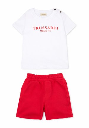 Camicia bianca a maniche corte con scritta rossa "TRUSSARDI Milano 1911" e due bottoni sulle spalle, abbinata a pantaloncini rossi con vita elastica.