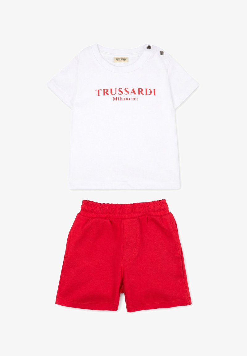 Chemise blanche à manches courtes avec texte rouge "TRUSSARDI Milano 1911" et deux boutons aux épaules, associée à un short rouge à taille élastique.
