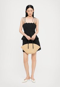 Rochie neagră cu peplum și tiv zimțat, purtată cu o geantă din paie cu o formă plată, în formă de evantai și mânere negre. Modelul poartă balerini albi.