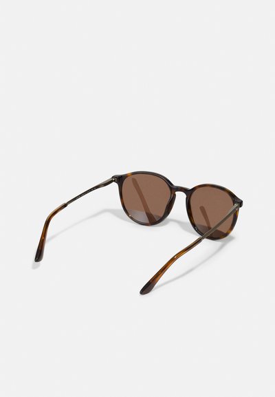 Brown-tinted sunglasses with round lenses and a tortoiseshell frame. Thin, sleek arms taper towards the tips, showcasing a glossy finish.