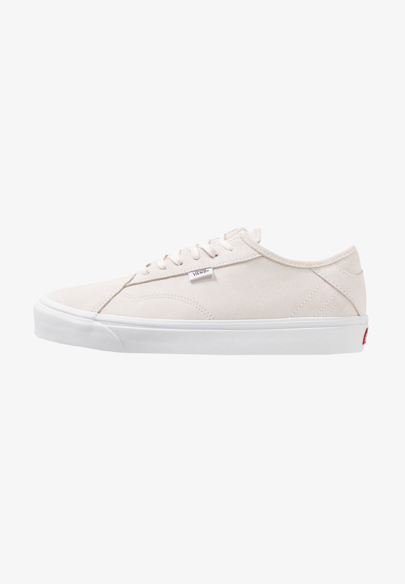 Basket basse blanche Vans avec un design à lacets, dessus en daim et semelle en caoutchouc blanche, montrée de côté sur fond blanc.