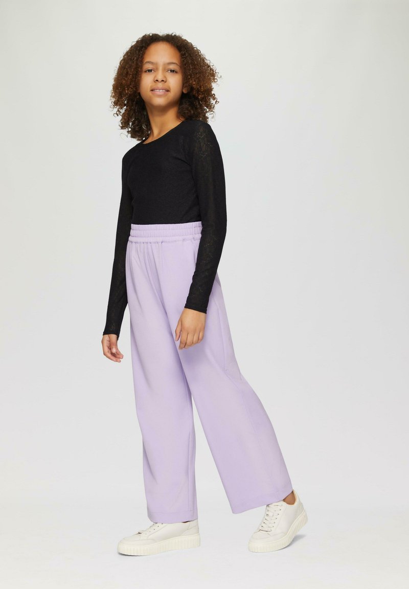 Zwarte lange mouwen shirt met een gestructureerde afwerking, gecombineerd met lavendel brede broek en witte sneakers.