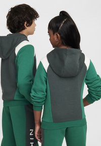 Grønn og grå hettegenser med kontrastfargede skulderpaneler, ribbede mansjetter og matchende bukser med en hvit logo.