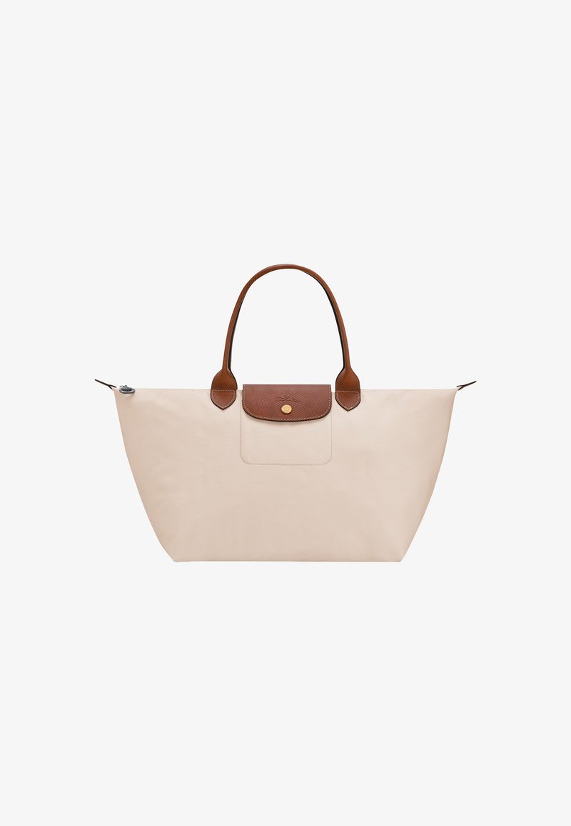 Beige tote bag with brown leather handles and flap, featuring a small gold button on the flap and a zipper closure on top.