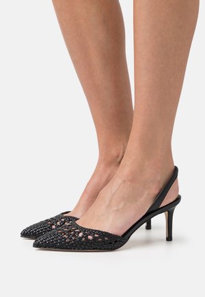 Tacones de esparto negros con tiras, de punta afilada, que presentan un patrón abierto en la parte superior y tacones delgados y afilados. Se aprecian acentos de piel suave.