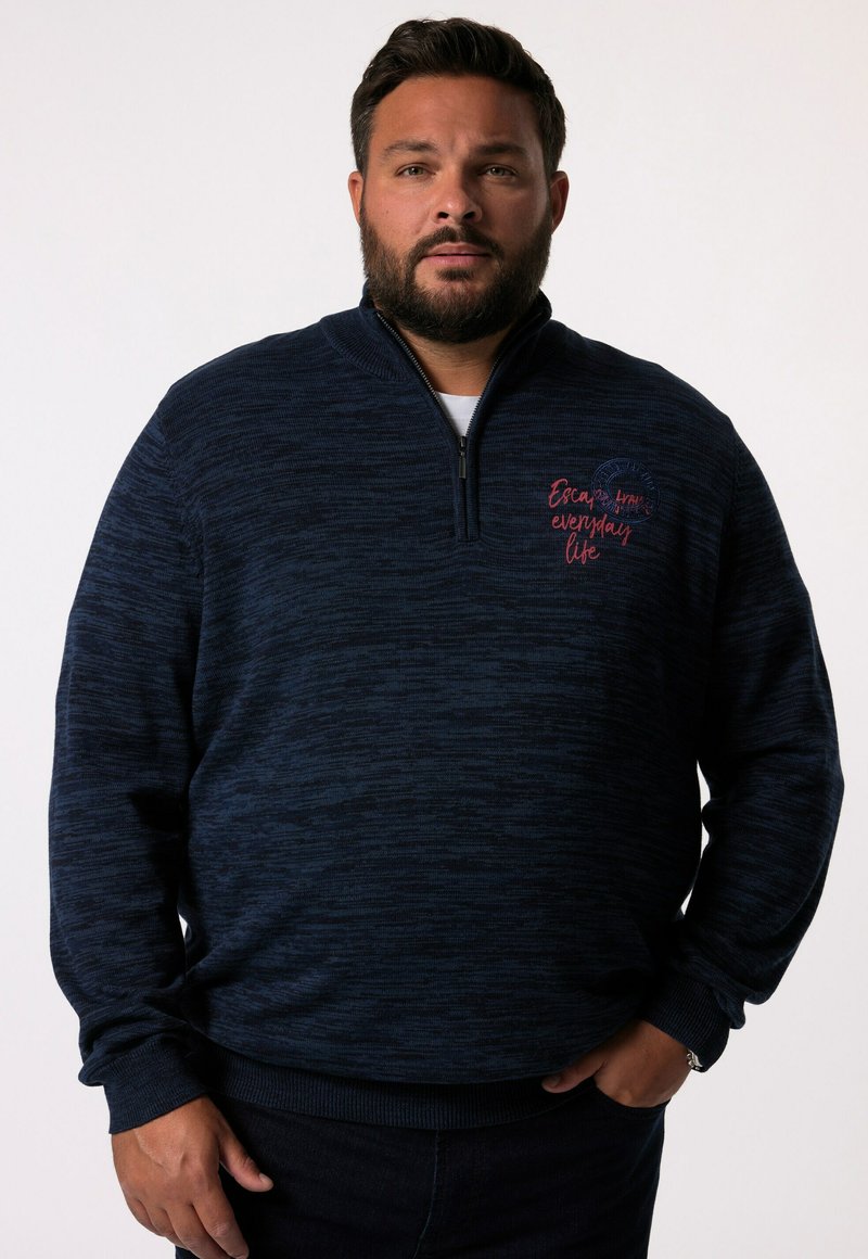 Marinblå zip-up tröja med texturerad yta. Har broderad text i röd, ståkrage samt ribbad ärm och nederkant.