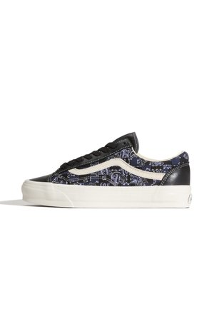Lage sneaker met zwart en marineblauw patchworkpatroon, witte zijstreep, zwarte veters en witte rubberen zool op een witte achtergrond.
