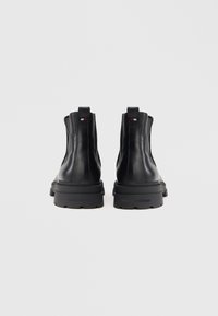 Botine negre din piele, cu talpă groasă, panouri elastice pe lateral și o bucată de material la spate pentru a fi mai ușor de încălțat. Logo-ul mărcii este vizibil pe talpă.