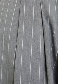 Grijze stof met verticale witte streepjes en een diepe plooi-detail, die textuur en vallende plooien toont.