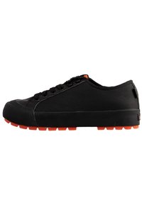Scarpe sportive nere con tomaia testurizzata, chiusura con lacci e suola in gomma arancione a contrasto. Punta arrotondata e design a profilo basso.
