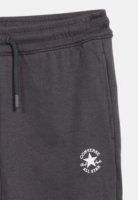 Φόρμες ανθρακί με ελαστική μέση, μαύρο κορδόνι, πλαϊνή τσέπη και λευκό λογότυπο Converse All Star Chuck Taylor στο μηρό.