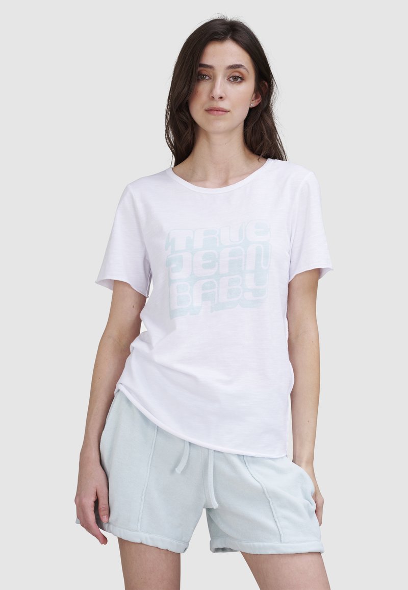 Witte t-shirt met korte mouwen, voorzien van een zachte, textuur afwerking en een lichtblauwe opdruk "TRUE JEAN BABY". Gecoördineerd met lichtblauwe shorts.