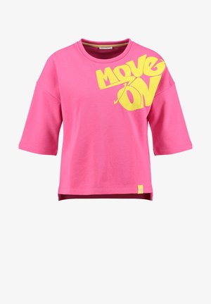 T-shirt court rose à manches courtes avec une coupe large et un grand texte jaune "MOVE ON" sur le haut du côté gauche de la poitrine.