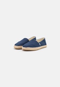 Marineblauwe canvas instapschoenen met een jute touwzool. Heeft een ronde neus en elastische zijpanelen voor gemakkelijk aan- en uittrekken.