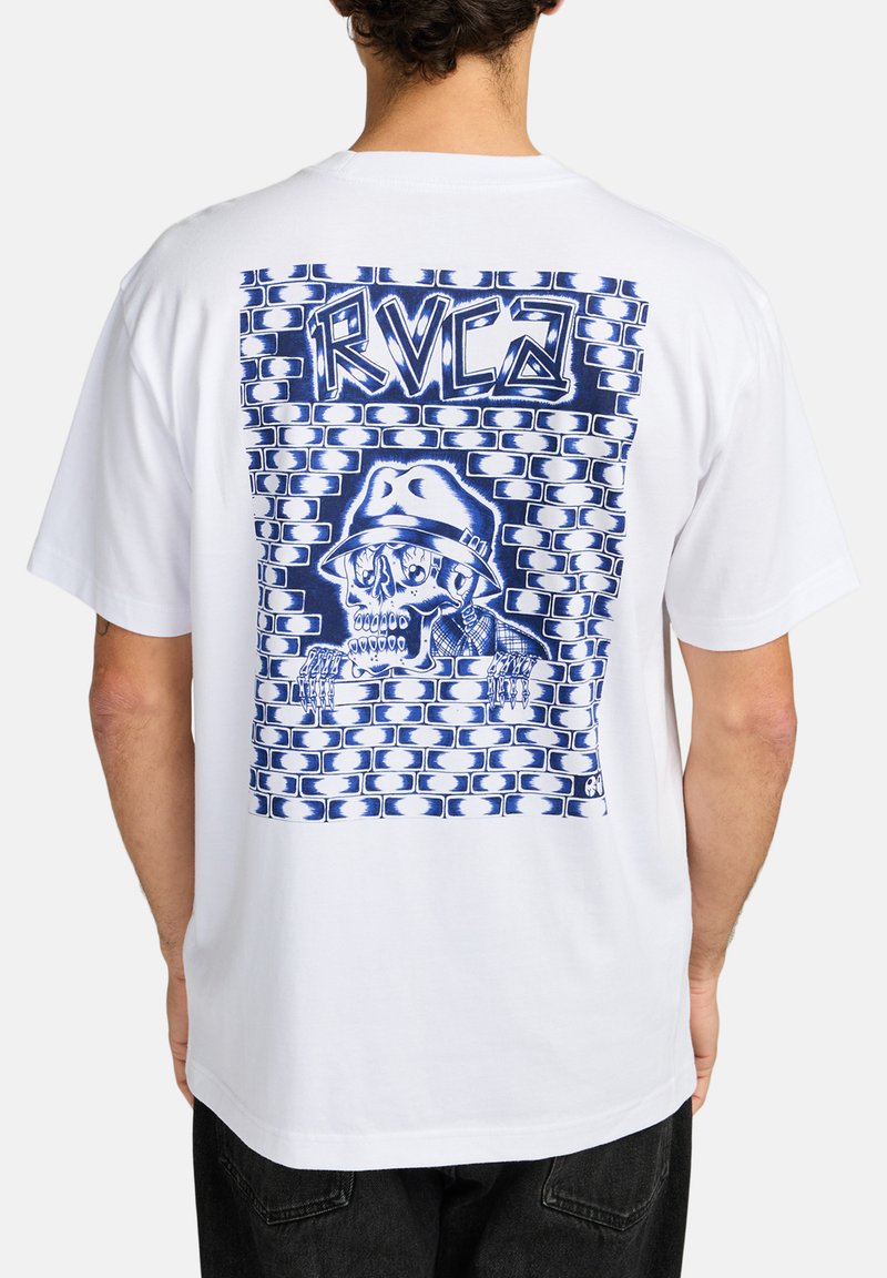 White cotton t-shirt featuring a blue graphic print of a skull wearing a hat, set against a brick wall design. Relaxed fit, short sleeves.