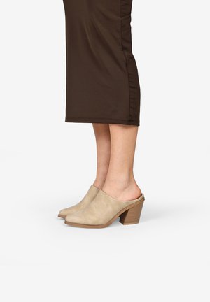 Mules de ante beige con puntera redondeada y parte trasera abierta, que cuentan con un tacón bloque texturizado y una superficie suave.