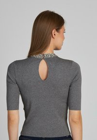 Top grigio in maglia a maniche corte con apertura a occhio di chiave sul retro e colletto decorato con accenti ornamentali.