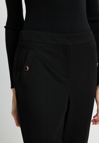 Zwarte op maat gemaakte broeken van een gladde stof, met een zijzak en een gouden accentknop. Fitted ontwerp met een elegante silhouette.
