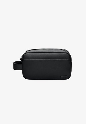 Pochette de voyage noire zippée en tissu texturé, avec une poignée latérale et un petit logo sur le devant.