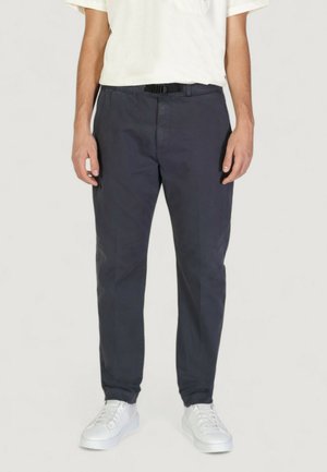 Pantaloni in cotone blu navy con gamba dritta, dotati di una cintura nera e dettagli che accentuano la vita. Abbinati a sneakers bianche.