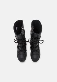 Svarta stövlar vid vaden i texturerat läder med fuskpälsfoder. Funktioner inkluderar snörning, dragkedjor och en gummisula.