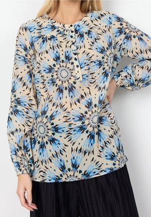 Blusa leggera e con motivo floreale in blu e nero su sfondo beige, con maniche lunghe e scollatura con bottoni.