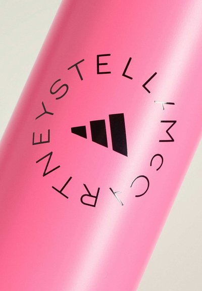 Contenitore cilindrico rosa con logo Adidas nero e testo "STELLA MCCARTNEY" curvato intorno.