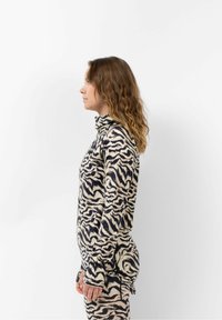 Turtleneck top in cr�ème en donkerblauw zebra patroon, met een aansluitend ontwerp en lange mouwen met duimopening, gemaakt van een zachte, gestructureerde stof.