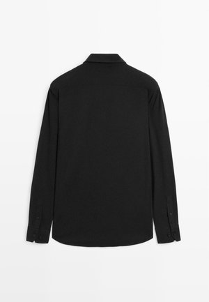 Chemise noire à manches longues avec un col classique, des poignets à boutons et une texture lisse ; la vue arrière montre un ourlet droit et des coutures discrètes.