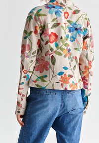 Beige jas met bloemenpatroon, gemaakt van lichtgewicht stof, met kleurrijke bloemen in verschillende tinten, voorzien van knoopmanchetten en een getailleerde pasvorm.