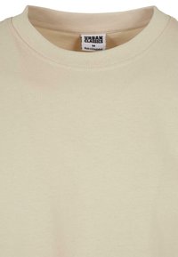 Beige T-skjorte laget av myk bomull, med klassisk rund hals. Merket viser merkevaren "Urban Classics" og størrelse "M."