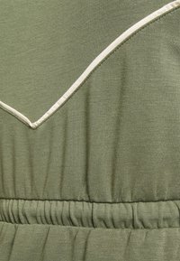Tecido de vestido verde-azeitona com acabamento texturizado. Apresenta um decote com bainha em creme e um detalhe de cintura elástica.
