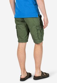 Grüne Cargo-Shorts mit mehreren Taschen, strukturiertem Stoff und lockerer Passform, kombiniert mit braunen verstellbaren Sandalen.