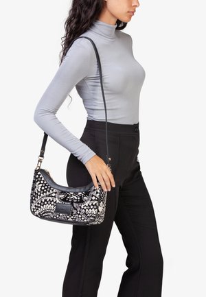 Borsa hobo in tessuto nero e bianco a fantasia con dettagli in pelle, dotata di chiusura con zip e una lunga tracolla regolabile per il trasporto a spalla.