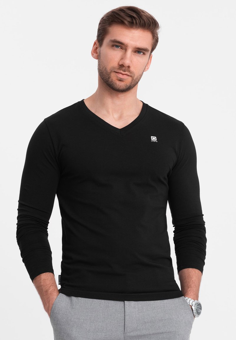 Schwarzes Langarm-V-Ausschnitt-Shirt aus weichem Stoff, mit kleinem Logo auf der Brust und tailliertem Design.