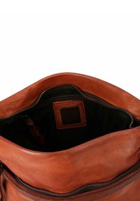 Borsa in pelle marrone con apertura superiore, interno in tessuto scuro visibile, tasca interna con zip e una toppa in pelle cucita con un logo ancora in rilievo.