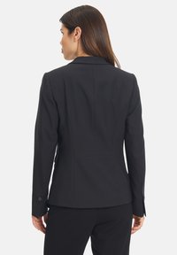 Černý upravený blazer se strukturovaným designem, hladkým materiálem, zapínáním na jeden knoflík a jemnými stehy na zadní straně.