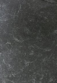 Tessuto rigato nero con una leggera lucentezza e variazioni di grigio chiaro; vista ravvicinata che mette in mostra linee verticali e texture.